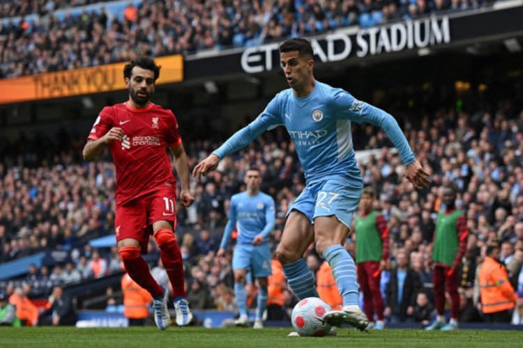 Liverpool's Egyptian midfielder Mohamed Salah (L) vies with Manchester City's Portuguese defender Joao Cancelo during the English Premier League football match between Manchester City and Liverpool at the Etihad Stadium in Manchester, north west England, on April 10, 2022. - RESTRICTED TO EDITORIAL USE. No use with unauthorized audio, video, data, fixture lists, club/league logos or 'live' services. Online in-match use limited to 120 images. An additional 40 images may be used in extra time. No video emulation. Social media in-match use limited to 120 images. An additional 40 images may be used in extra time. No use in betting publications, games or single club/league/player publications. (Photo by Paul ELLIS / AFP) / RESTRICTED TO EDITORIAL USE. No use with unauthorized audio, video, data, fixture lists, club/league logos or 'live' services. Online in-match use limited to 120 images. An additional 40 images may be used in extra time. No video emulation. Social media in-match use limited to 120 images. An additional 40 images may be used in extra time. No use in betting publications, games or single club/league/player publications. / RESTRICTED TO EDITORIAL USE. No use with unauthorized audio, video, data, fixture lists, club/league logos or 'live' services. Online in-match use limited to 120 images. An additional 40 images may be used in extra time. No video emulation. Social media in-match use limited to 120 images. An additional 40 images may be used in extra time. No use in betting publications, games or single club/league/player publications. (Photo by PAUL ELLIS/AFP via Getty Images)