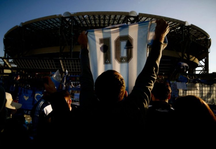 TOPSHOT - A man holds a jersey of Argentina's national football team with Diego Maradona's number 10 as people gather outside the San Paolo stadium in Naples on November 26, 2020 to mourn the death of late Argentinian football legend Diego Maradona. - Maradona, widely remembered for his "Hand of God" goal against England in the 1986 World Cup quarter-finals, died on November 25, 2020 of a heart attack at his home near Buenos Aires in Argentina, while recovering from surgery to remove a blood clot on his brain. (Photo by Filippo MONTEFORTE / AFP) (Photo by FILIPPO MONTEFORTE/AFP via Getty Images)