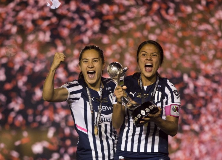 Desiree Monsivais (L) and Rebeca Bernal (R) of Rayadas of Monterrey celebrate with the trophy after winning the Liga MX Femenil Apertura 2021 football tournament by defeating Tigres at Universitario stadium in Monterrey, Mexico, on December 20, 2021. (Photo by Julio Cesar AGUILAR / AFP) (Photo by JULIO CESAR AGUILAR/AFP via Getty Images)
