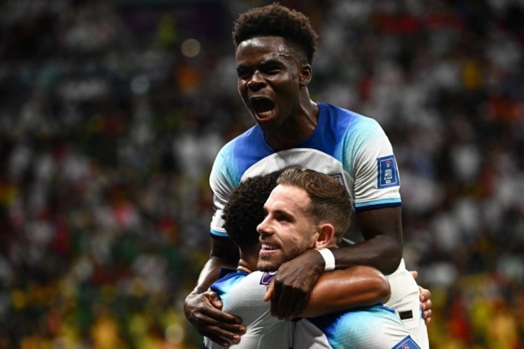 TOPSHOT - England's midfielder #08 Jordan Henderson (bottom) celebrates with England's forward #17 Bukayo Saka after he scored his team's first goal during the Qatar 2022 World Cup round of 16 football match between England and Senegal at the Al-Bayt Stadium in Al Khor, north of Doha on December 4, 2022. (Photo by Anne-Christine POUJOULAT / AFP) (Photo by ANNE-CHRISTINE POUJOULAT/AFP via Getty Images)